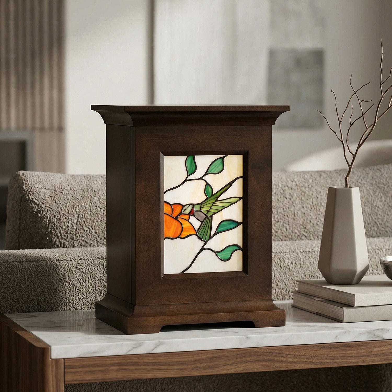 Decorative urn with stained glass panel featuring a hummingbird on a marble top sofa table.