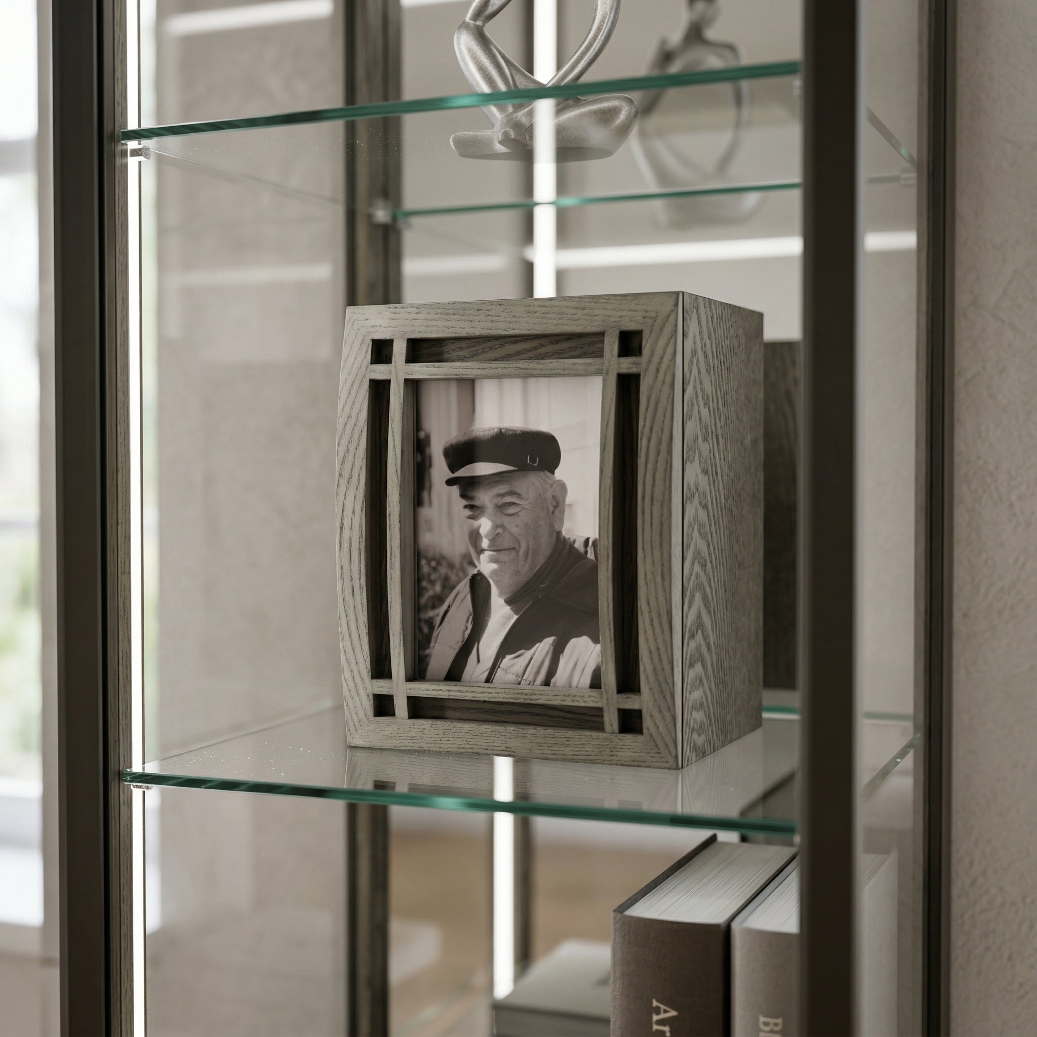 Wooden curved portrait urn with a black and white photo of an elderly man on a glass shelf.