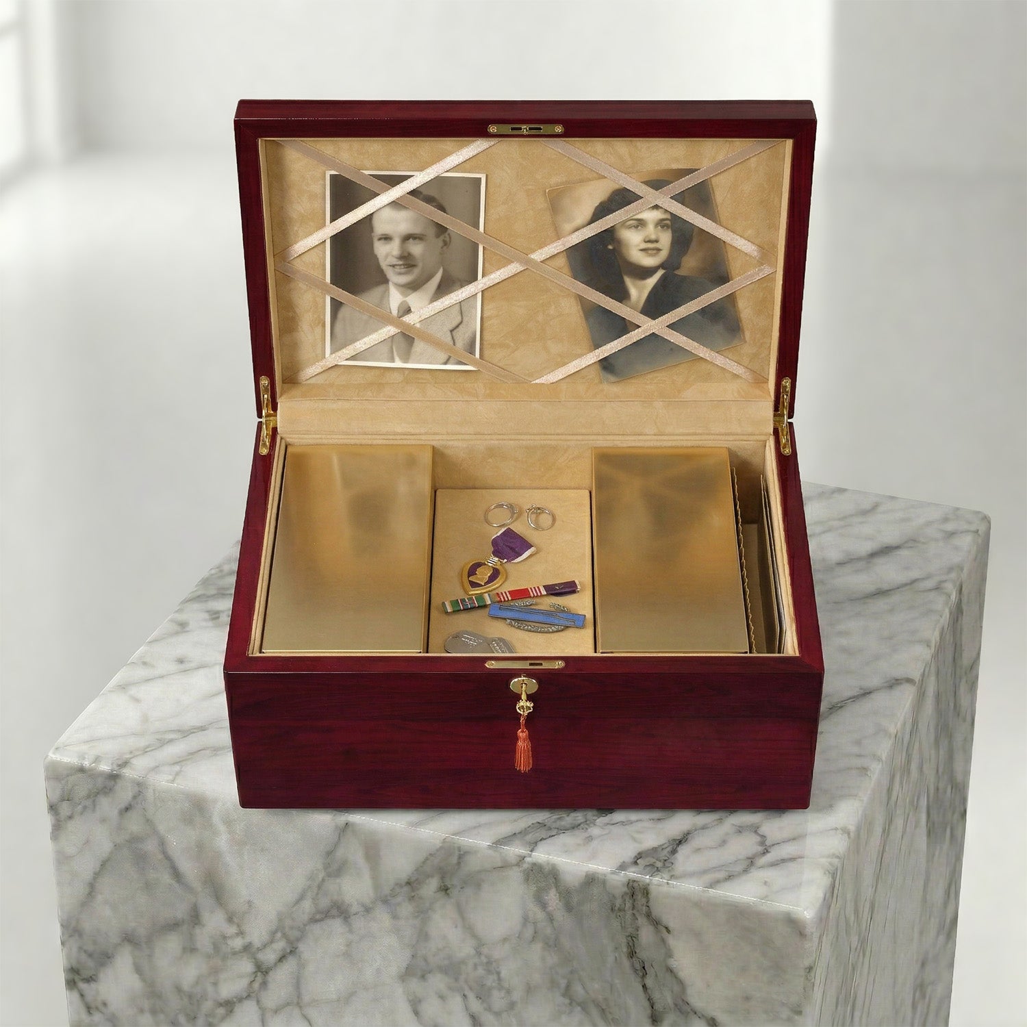 Wooden urn box with gold interior, containing jewelry and photos on a marble surface.