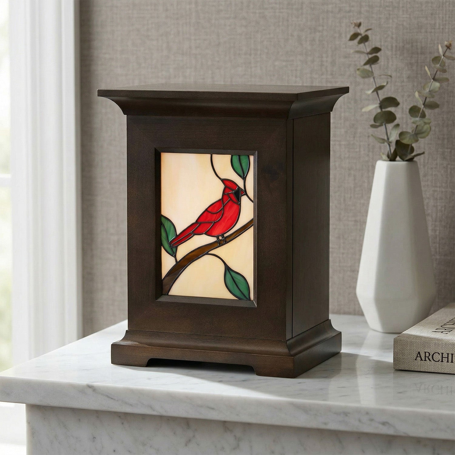 Decorative urn with stained glass design of a red cardinal on a marble table.
