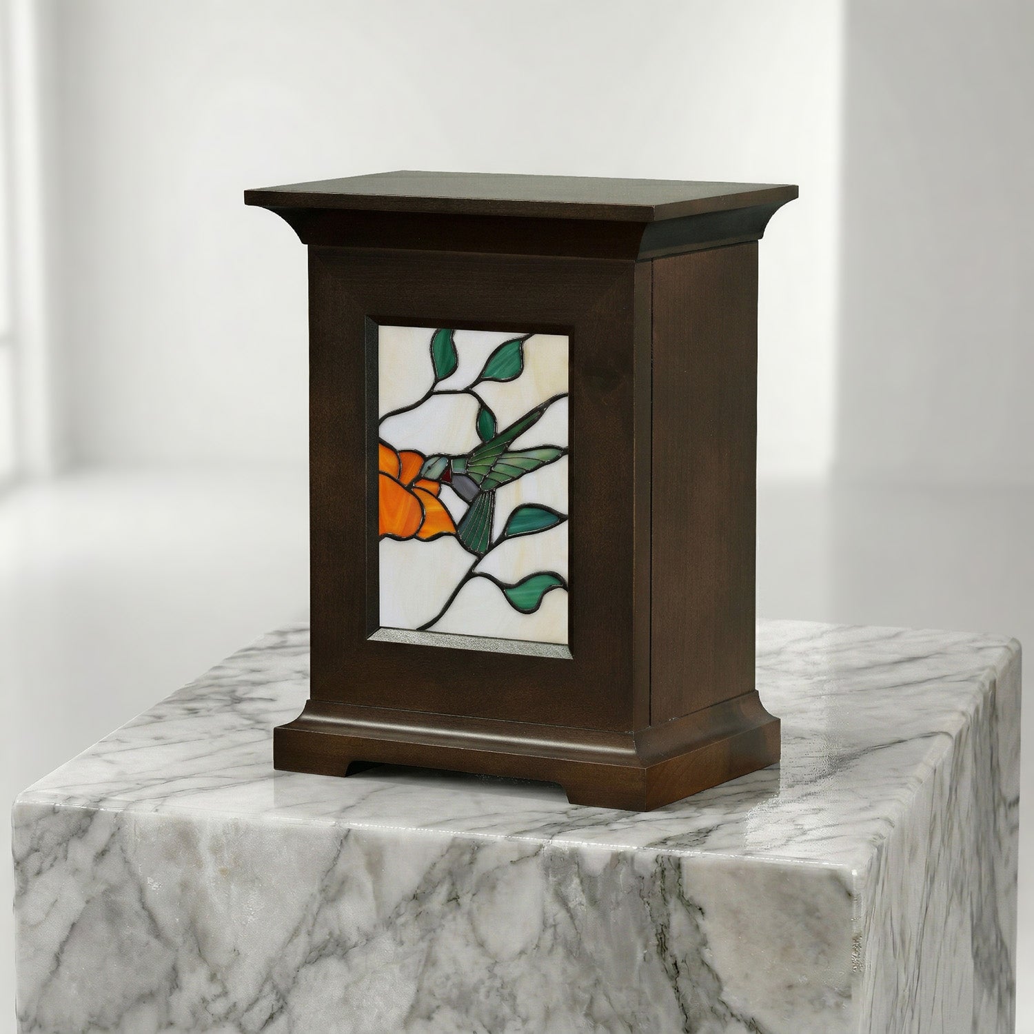 Decorative urn with stained glass panel featuring a hummingbird on a marble surface